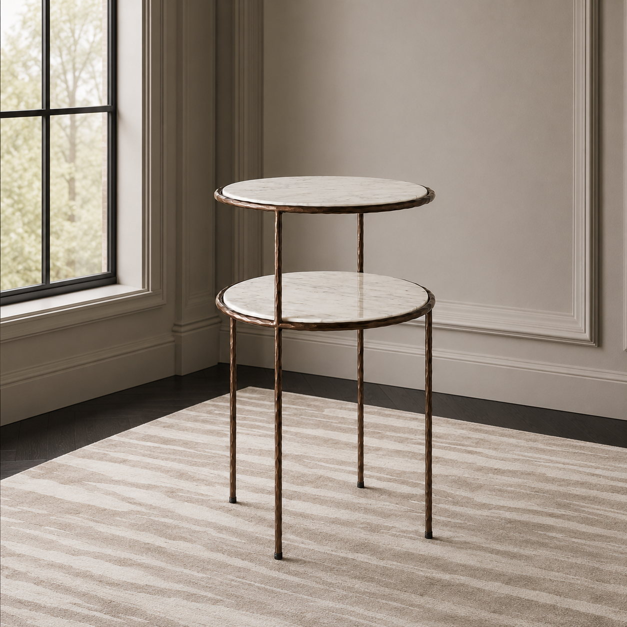 A two-tier nesting side table with round white marble-look tops and distressed bronze metal legs, shown in a styled interior room with a window, paneled wall, and striped rug.