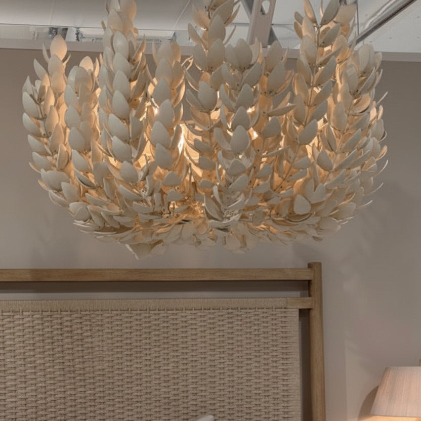 Chandelier hanging above a bed with neutral bedding and decor.