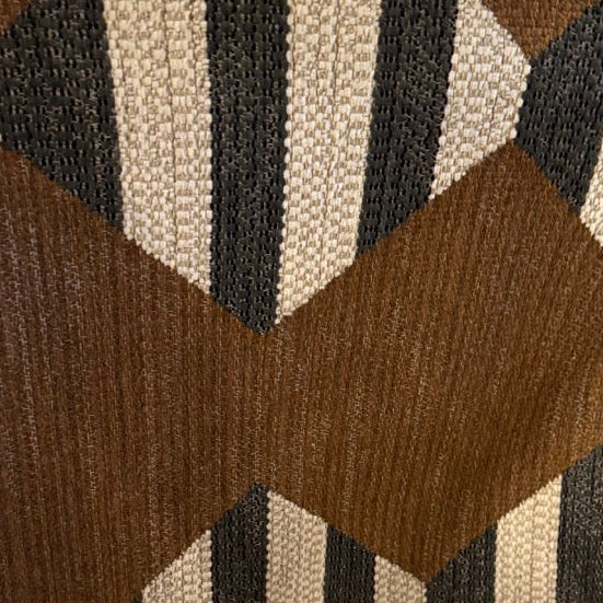 Textile sample with geometric pattern held by a hand on a wooden surface