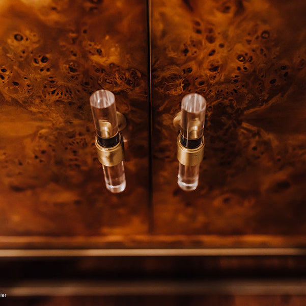 Close-up of a wooden cabinet with glass knobs on a textured brown background