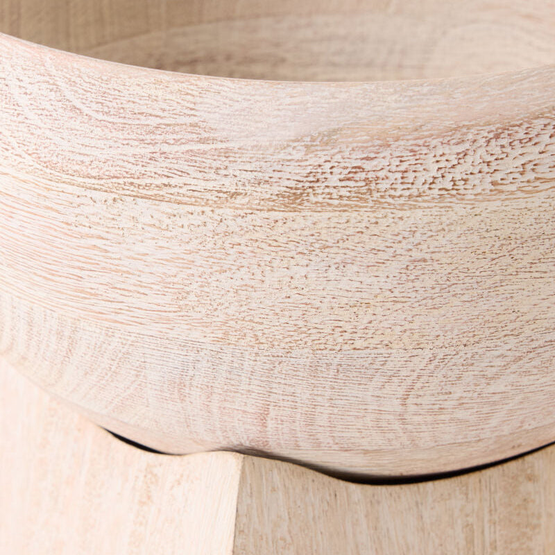 Close-up of a light natural wood bowl showing the grain texture and curved rim, resting on a matching wooden surface.
