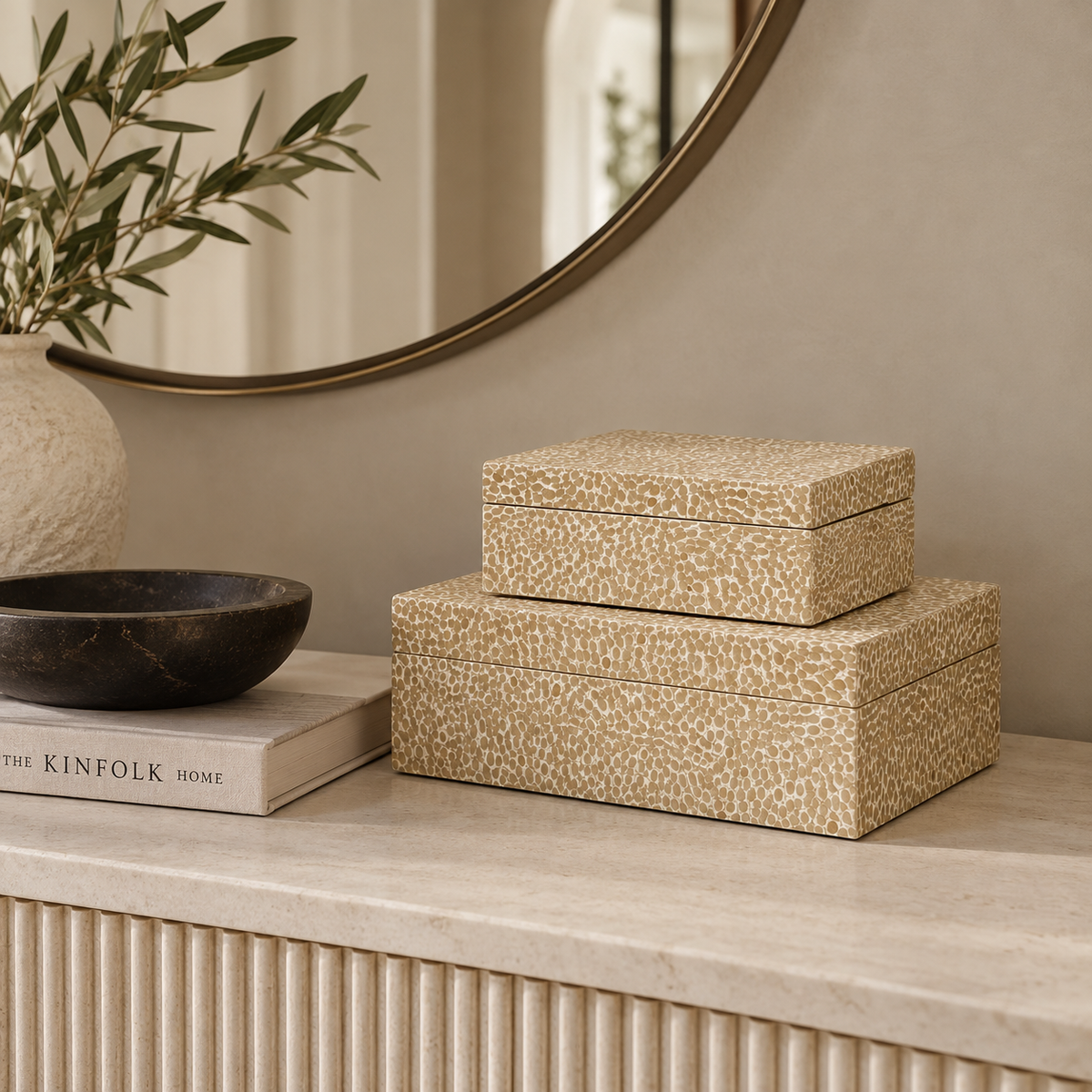 Two stacked rectangular storage boxes with a textured beige and cream animal-print pattern, displayed on a light stone console table in a styled interior setting.