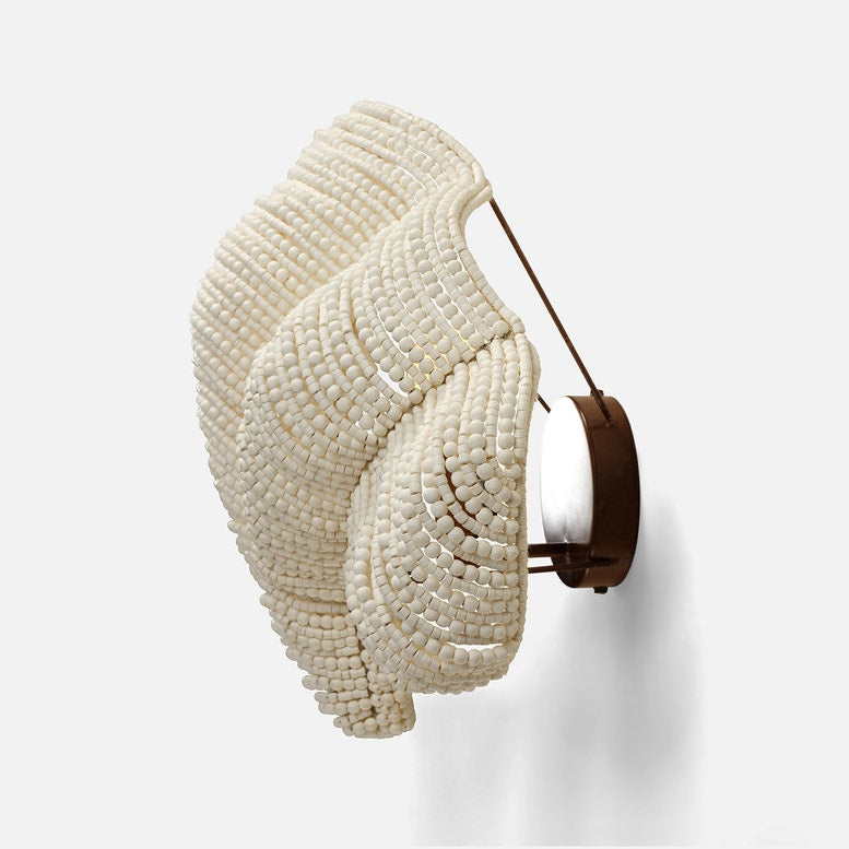 Decorative wall sconce with white beaded design and brown leather strap on a white background