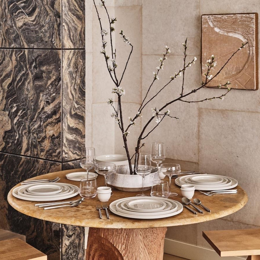 Dining table set with plates, glasses, and cutlery in a modern kitchen.