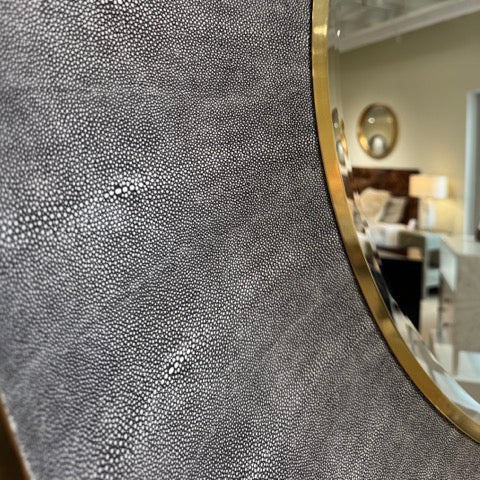 Close-up of a textured wall panel with a gold frame, interior setting in the background.