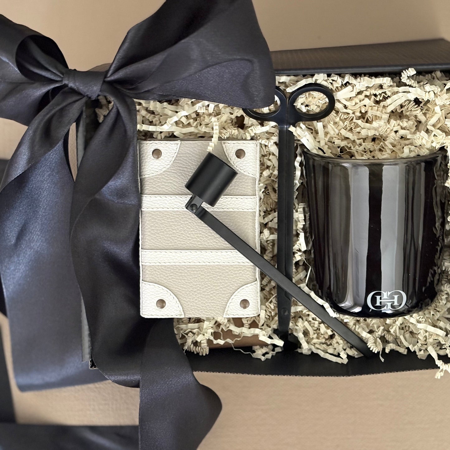 Black candle in a decorative box with a black ribbon on a beige background