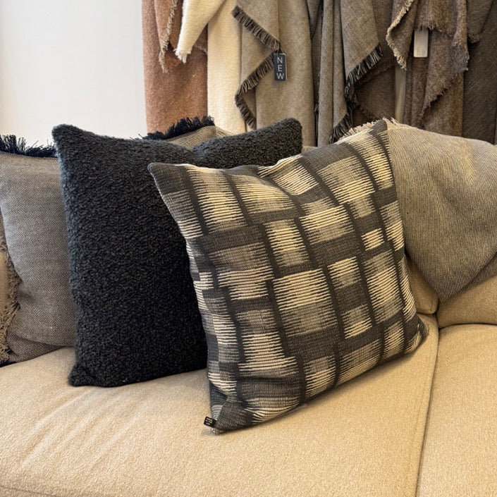 Beige sofa with patterned cushions and throws in a store setting