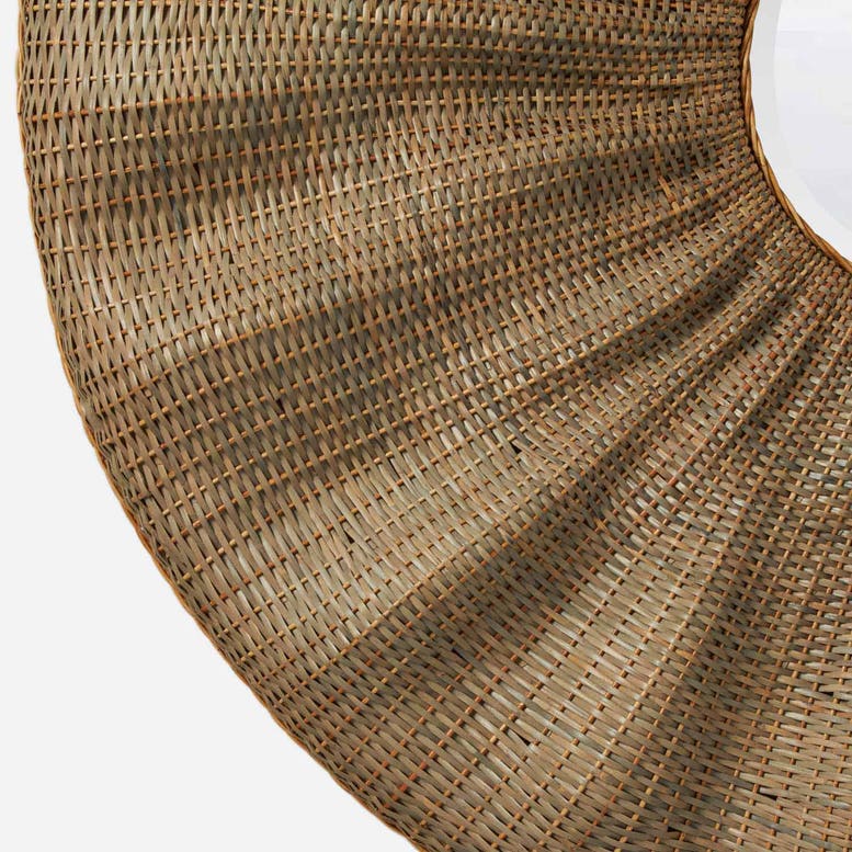 A close-up of a woven circular rug or mat in natural tan and brown tones, showing the detailed texture of the fibers against a plain white background.