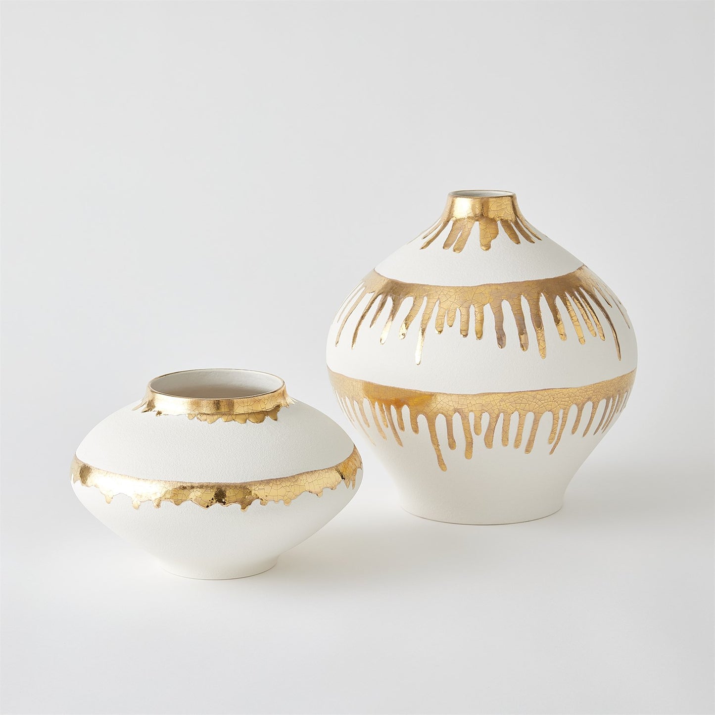 Two white vases with gold decorative patterns on a light gray background