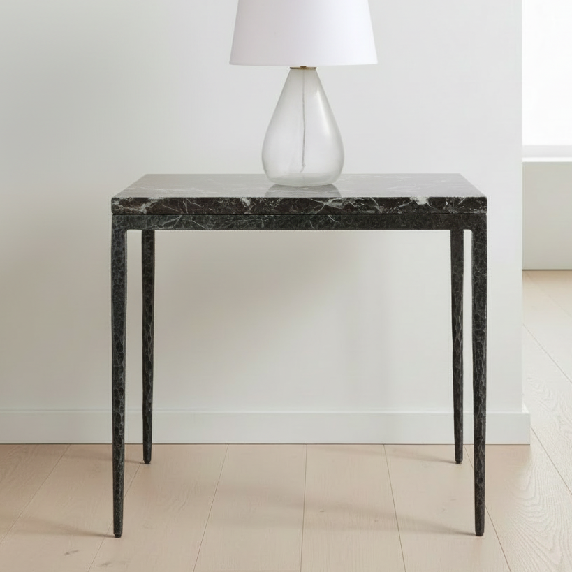 Black marble side table with a white lamp against a white wall.