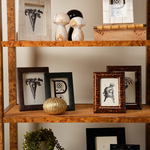 Decorative wooden shelf with framed pictures, sculptures, and a gold vase.