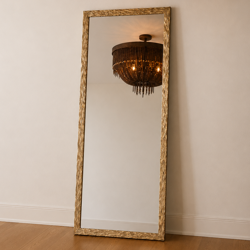 A dark bronze chandelier with hanging fringe is shown hanging from the ceiling, with a tall floor mirror below reflecting the light. The room has off-white walls and light wood flooring.