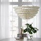 Chandelier hanging above a table with decorative vases and a plant in a bright room.