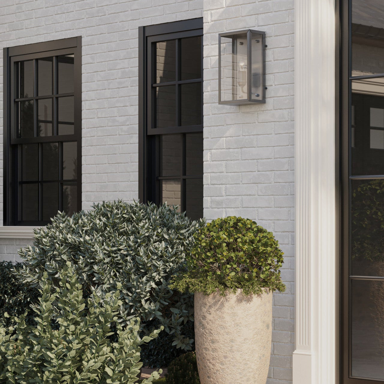 Decorative planters with greenery in front of a light gray brick building.