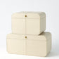 Two cream-colored jewelry boxes with gold accents on a white background