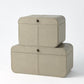 Two beige leather storage boxes stacked on a white background