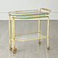 Gold bar cart with glass shelves on a wooden floor