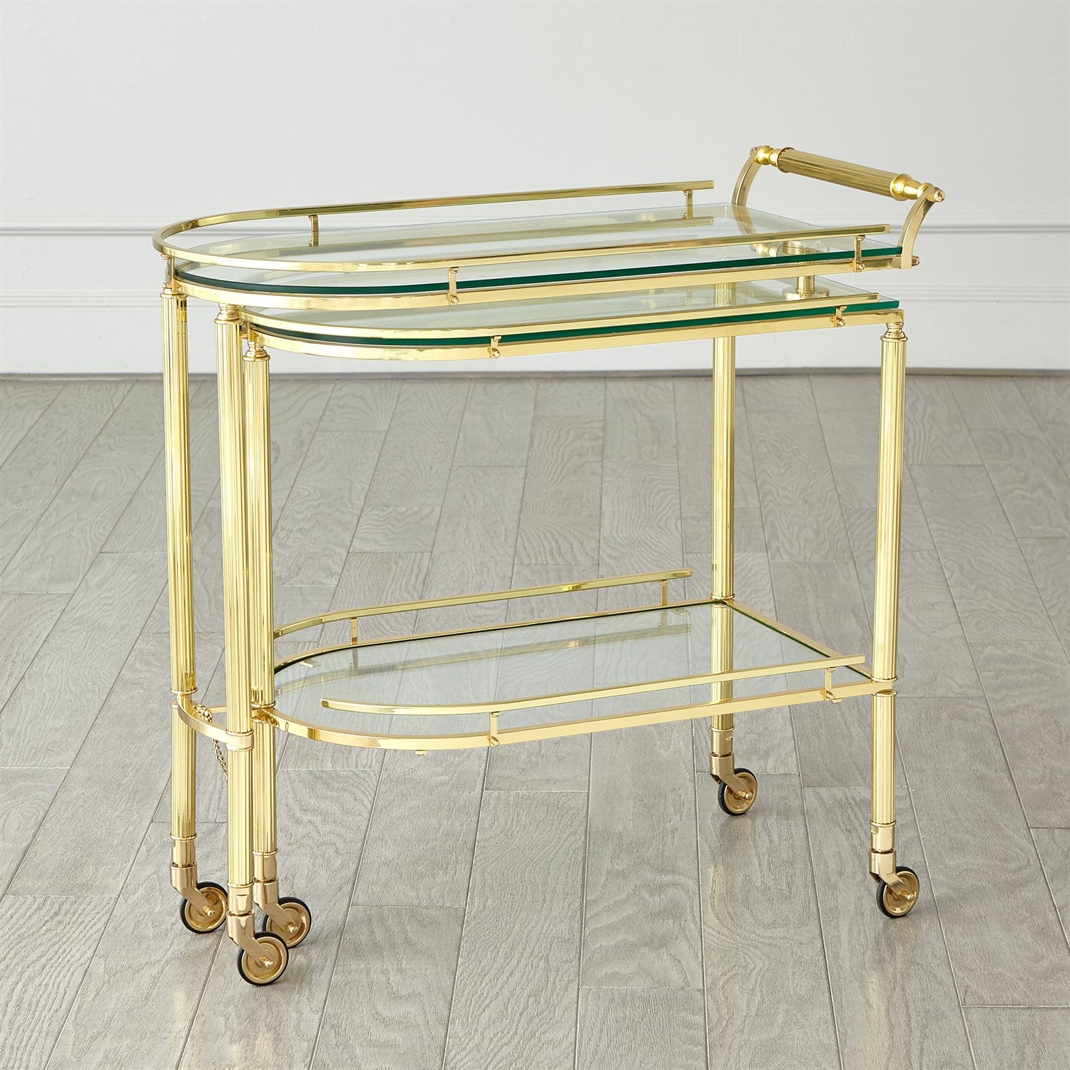 Gold bar cart with glass shelves on a wooden floor