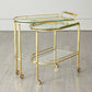 Gold serving cart with glass shelves on a wooden floor