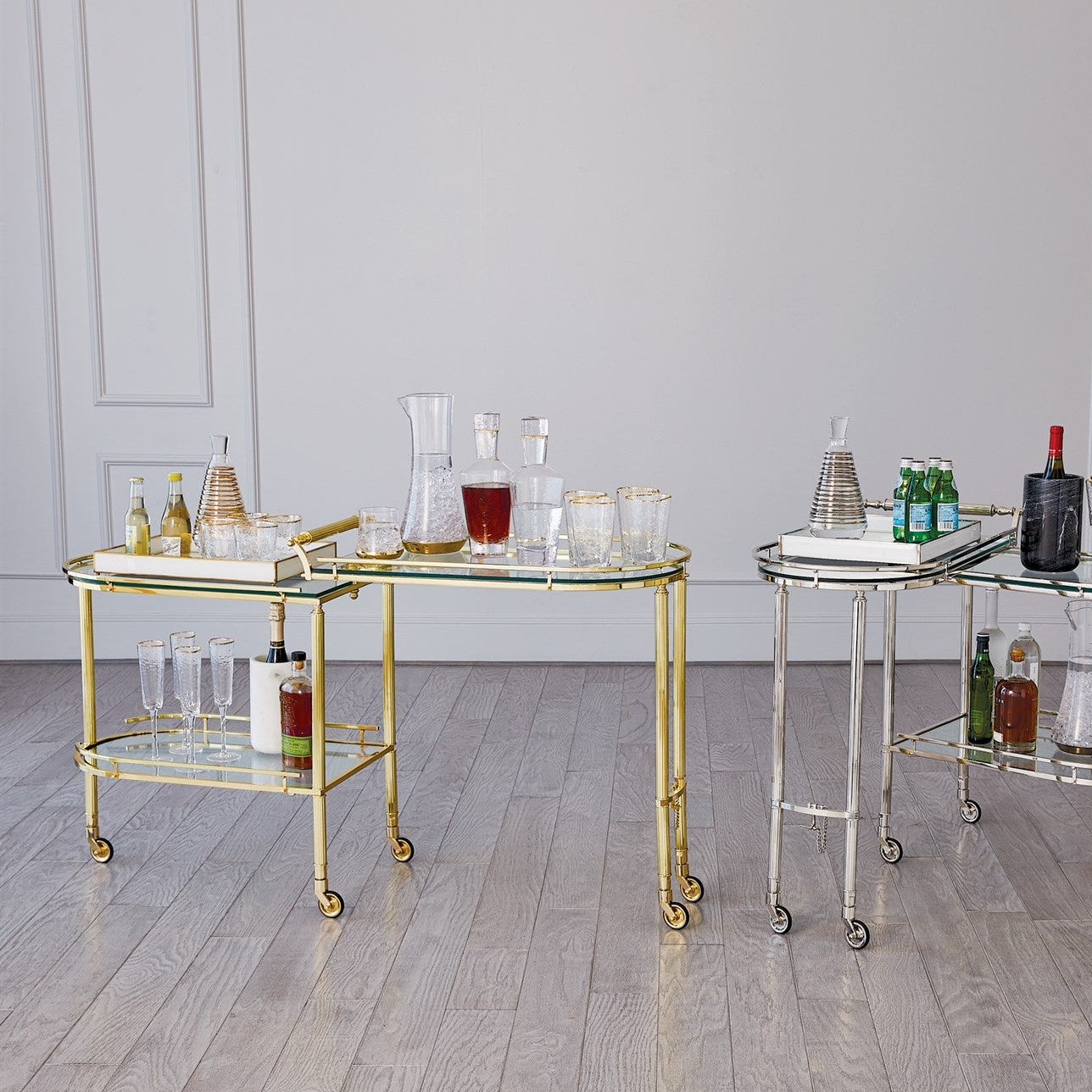 Two glass serving carts with drinks and glasses on a wooden floor.