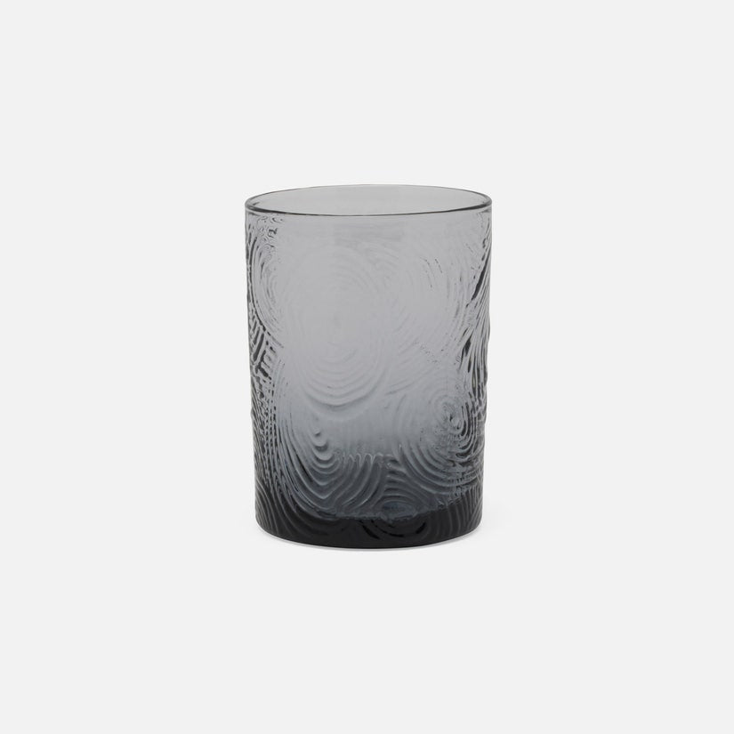 Gray glass tumbler with textured design on a white background