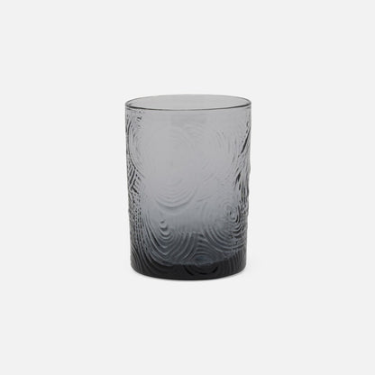 Gray glass tumbler with textured design on a white background