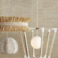 Modern pendant light with decorative elements against a textured beige wall.