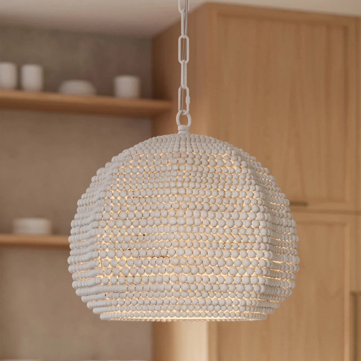 Beaded pendant light hanging in a kitchen setting with wooden cabinets and shelves.