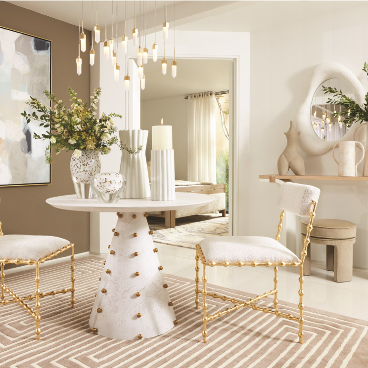 Dining room with gold chairs, white table, and decorative elements.