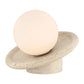 Lamp with a spherical white bulb on a textured beige base against a white background