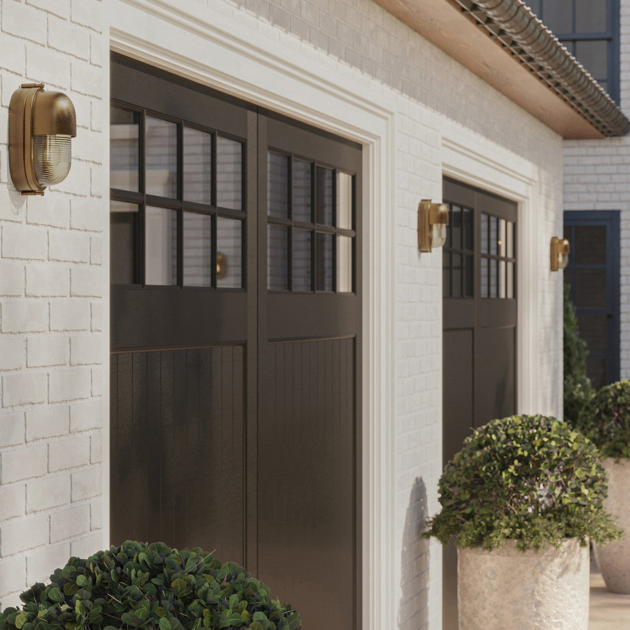 Pair of dark brown garage doors on a light brick wall with decorative lights.