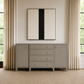 A light gray wooden sideboard cabinet with five drawers and two side panels, accented with small gold knobs, positioned against a beige wall in a styled room with beige curtains and a framed abstract print above.