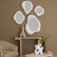 Decorative wall mirrors and sculptures on a brown wall with a beige sofa and table.
