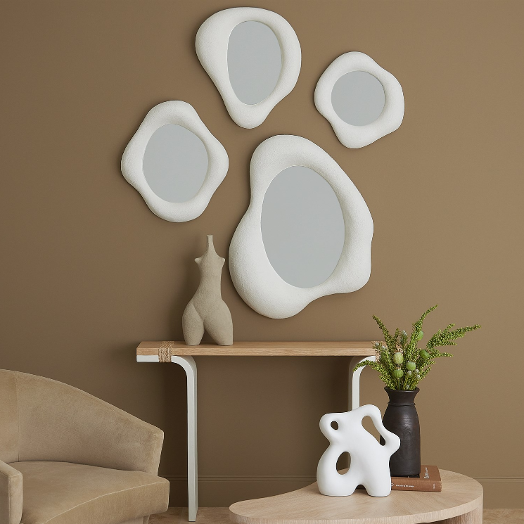 Decorative wall mirrors and sculptures on a brown wall with a beige sofa and table.