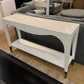 White console table with a shelf in a room with gray furniture and a rug.