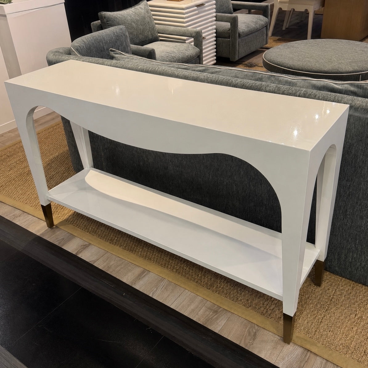 White console table with a shelf in a room with gray furniture and a rug.