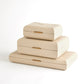 Stack of three beige jewelry boxes with gold accents on a white background