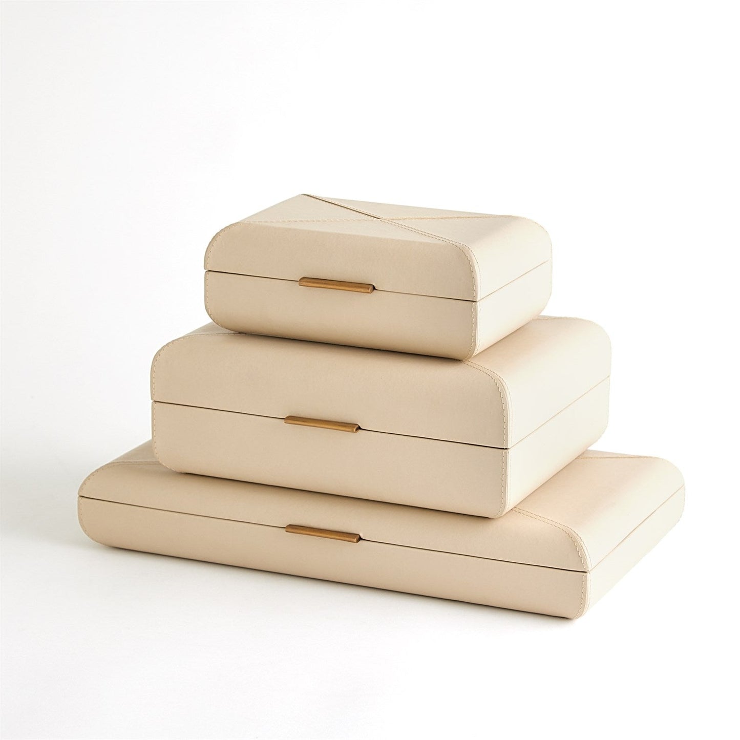 Stack of three beige jewelry boxes with gold accents on a white background