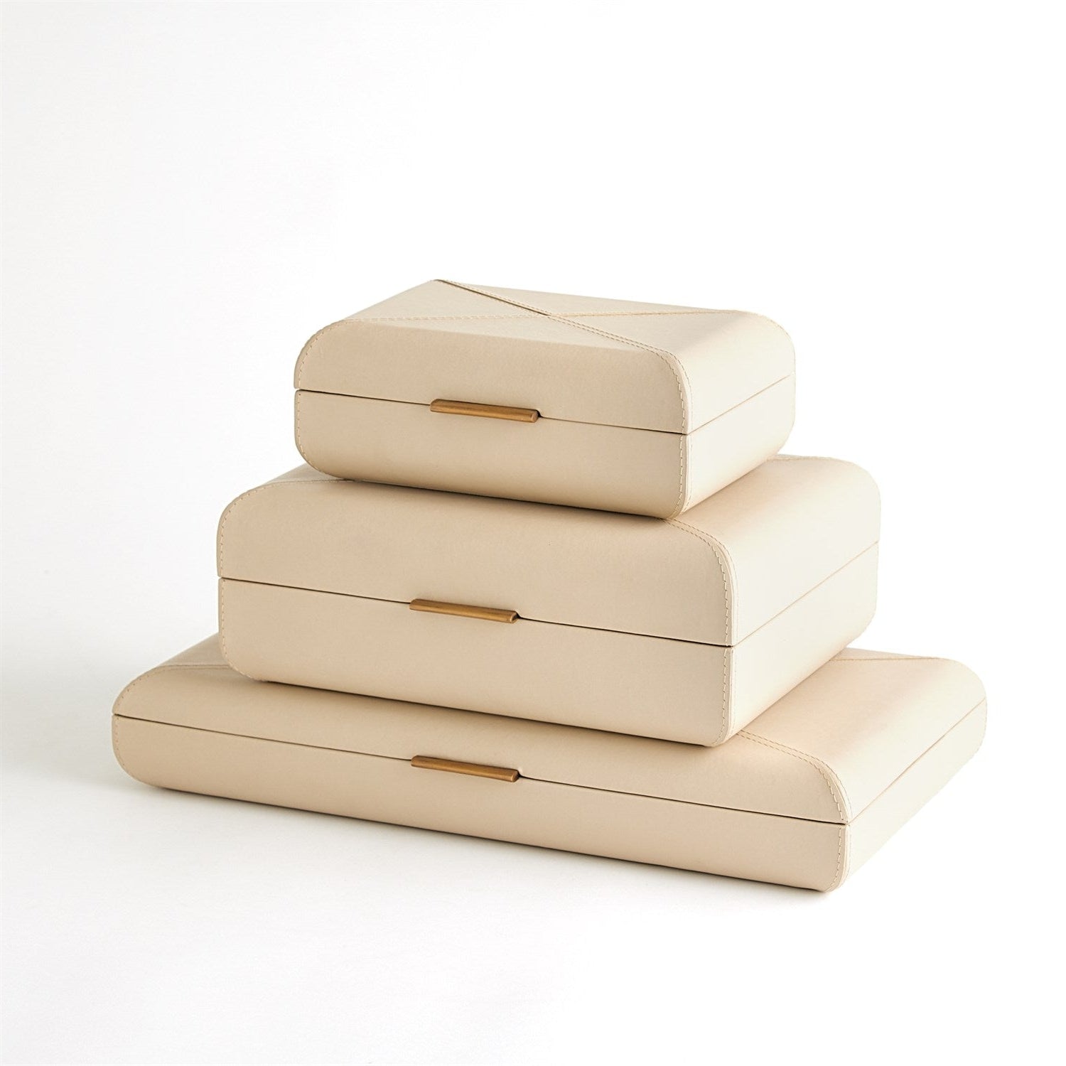 Stack of three beige jewelry boxes with gold accents on a white background