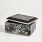 Marble-patterned jewelry box with a black and gold lid on a white background