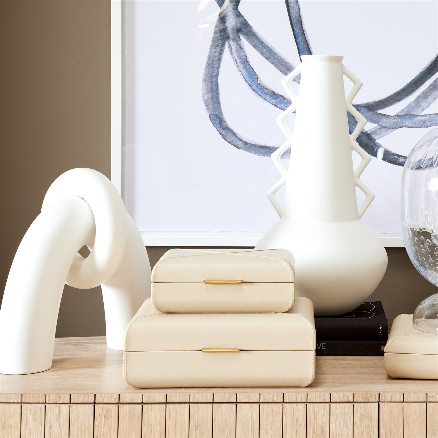 Decorative items including a white vase, a sculpture, and a stack of boxes on a wooden surface.