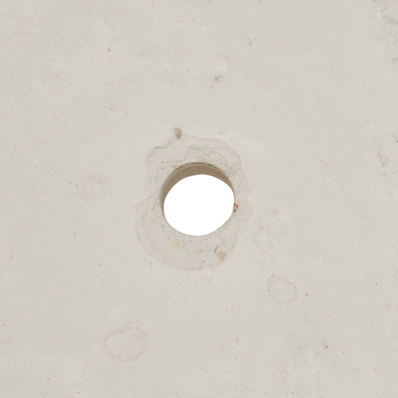 A close-up of a light beige textured surface with a circular hole in the center.