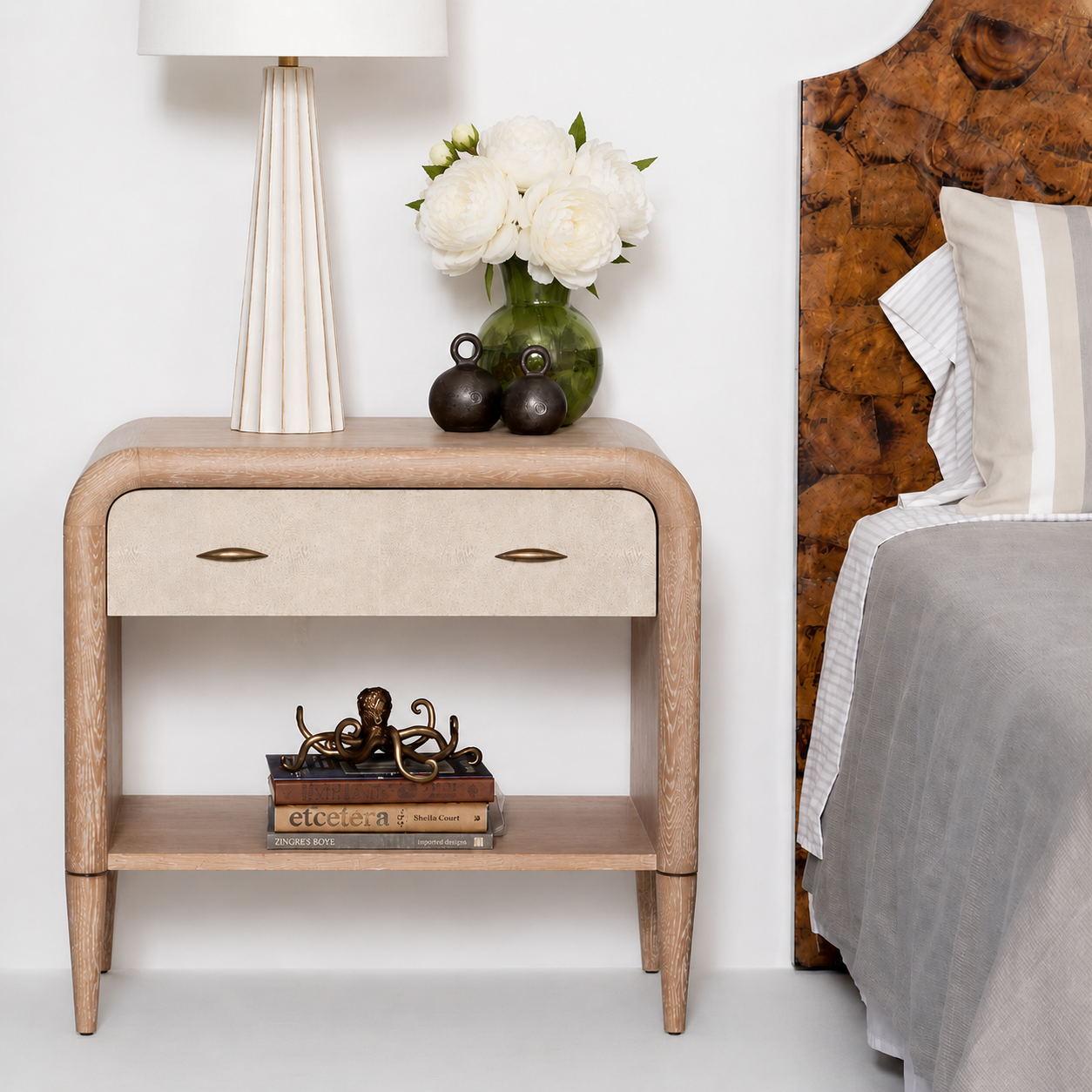 Wooden nightstand with decorative items next to a bed with a wooden headboard.