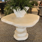 Decorative stone pedestal table with a potted plant in an indoor setting