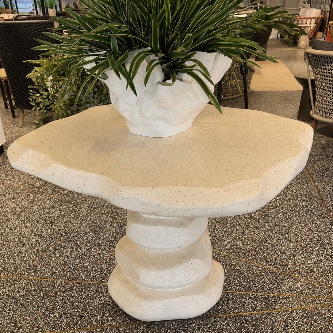 Decorative stone pedestal table with a potted plant in an indoor setting