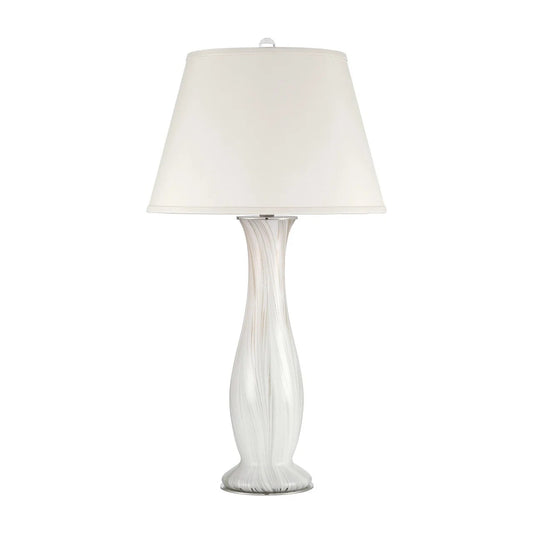 A table lamp with a tapered off-white fabric shade and a sculptural, fluted glass base in white and clear glass, set against a plain white background.