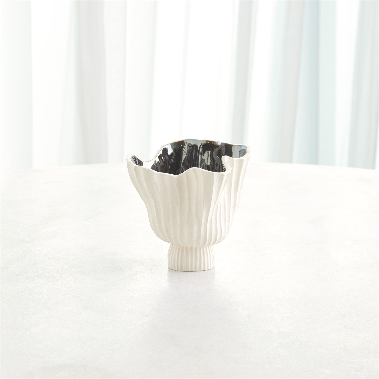 White ceramic vase with black interior against a white background