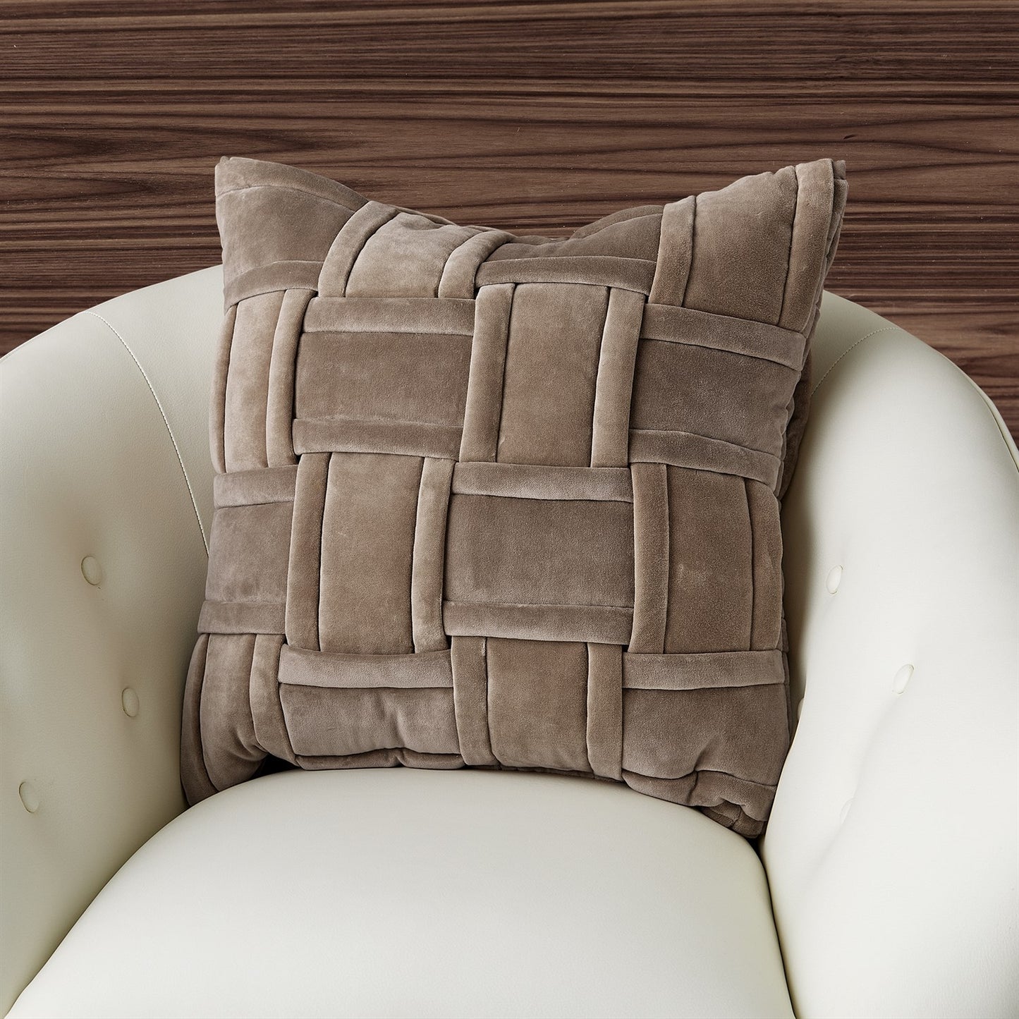 Brown woven pillow on a white chair with a wooden background