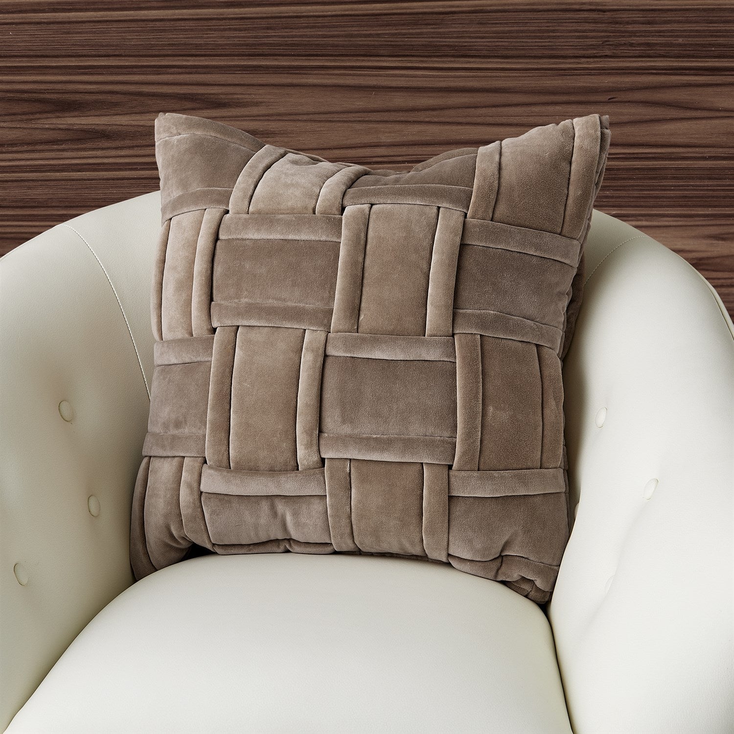 Brown woven pillow on a white chair with a wooden background