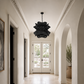 Elegant hallway with a black chandelier, white walls, and a large window.